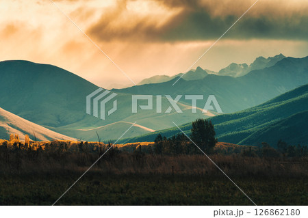 View of golden sunset sky shining on mountain range in countryside View of golden sunset sky shining on mountain range in countryside 126862180