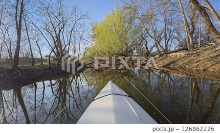 early spring kayaking or canoeing on a calm river with driftwood and fallen trees in Colorado - POV paddler perspective early spring kayaking or canoeing on a calm river with driftwood and fallen trees in Colorado - POV paddler perspective 126862226
