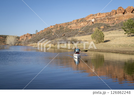 lonely paddler in an expedition canoe on Horsetooth Reservoir at foothills of Rocky Mountains in early spring scenery 126862248