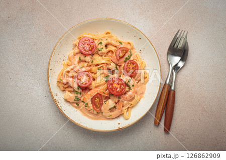 Seafood pasta linguine with shrimps and cherry tomatoes in creamy sauce garnished with parsley on white plate on light warm beige background top view Seafood pasta linguine with shrimps and cherry tomatoes in creamy sauce garnished with parsley on white plate on light warm beige background top view 126862909