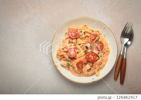 Seafood pasta linguine with shrimps and cherry tomatoes in creamy sauce garnished with parsley on white plate on light warm beige background top view, space for text Seafood pasta linguine with shrimps and cherry tomatoes in creamy sauce garnished with parsley on white plate on light warm beige background top view, space for text 126862917