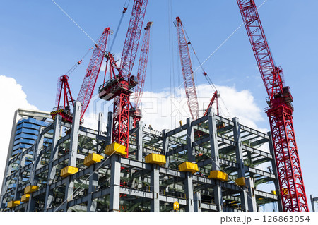 Low-angle view of cranes and steel structures of building construction with a blue sky background in Taiwan. 126863054