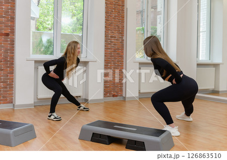Two women doing side lunges during fitness workout. 126863510