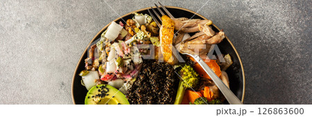 A vibrant, protein-packed breakfast with black quinoa, avocado, chicken, roasted veggies like sweet potato, broccoli, and a fresh salad of cabbage, radish, chia, and sesame seeds, banner 126863600