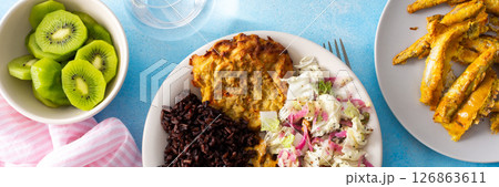 A balanced and nutritious breakfast with brown rice, baked white fish, fresh zucchini-carrot pancakes, a Chinese cabbage salad, and a sweet kiwi dessert, providing a perfect energy boost, banner A balanced and nutritious breakfast with brown rice, baked white fish, fresh zucchini-carrot pancakes, a Chinese cabbage salad, and a sweet kiwi dessert, providing a perfect energy boost, banner 126863611