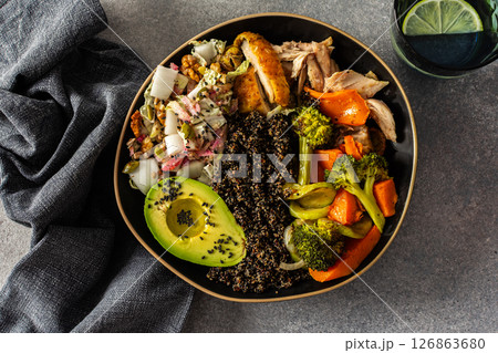Nutritious, wholesome breakfast featuring quinoa, avocado, roast chicken, and roasted vegetables like sweet potato, zucchini, and broccoli, complemented with a fresh cabbage and radish salad 126863680