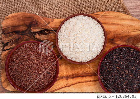 set of red and black and white rice, in a bowl, on a wooden surface, rustic style, top view 126864303