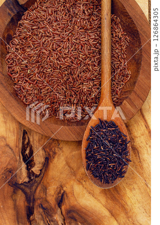 Red and black rice, in a wooden bowl and spoon on a wooden surface in rustic style, top view Red and black rice, in a wooden bowl and spoon on a wooden surface in rustic style, top view 126864305