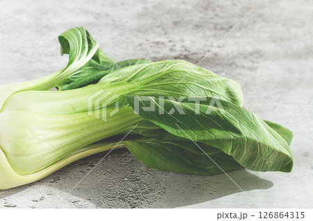 Fresh bok choy, laid out on a light gray surface, top view, natural light, 126864315