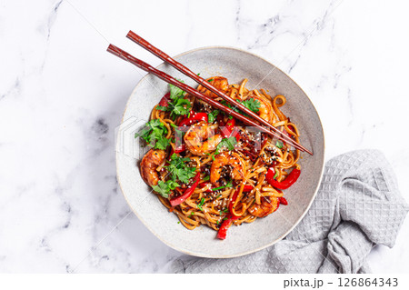 udon noodles, shrimp with vegetables and fresh herbs, in a bowl with chopsticks, light background, homemade, no people, 126864343