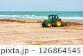 Spain, Valencia, March 29, 2024: Tractor Leveling Sand on a Beach by the Ocean on a Clear Day 126864545