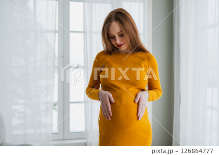 Pregnancy motherhood people expectation future. Pregnant woman with big belly standing near window at home. Girl hugging her tummy enjoying pregnancy. Maternity tenderness parenthood new life concept 126864777