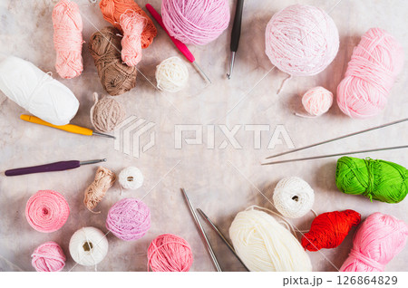 Frame of colored balls of wool and cotton, hooks and knitting needles on the table top view 126864829