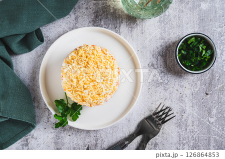 Traditional layered salad with canned fish on a plate on the table top view 126864853