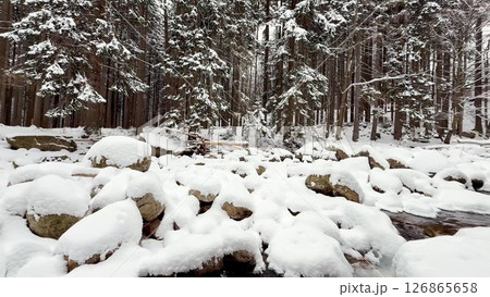 A beautiful winter wonderland filled with snowcovered rocks beside a scenic stream awaits you A beautiful winter wonderland filled with snowcovered rocks beside a scenic stream awaits you 126865658