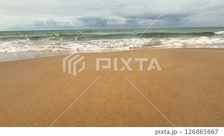 The Calm Beach Waves at Dusk Gently Crash Against the Shoreline, Surrounded by Golden Sand 126865667