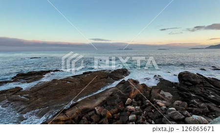 A Beautifully Serene Coastal Landscape at Dusk with Ocean Waves Crashing on Rocky Shoreline 126865671