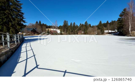 A Stunningly Beautiful Frozen Lake Under a Clear Blue Sky in a Serene Winter Landscape A Stunningly Beautiful Frozen Lake Under a Clear Blue Sky in a Serene Winter Landscape 126865740