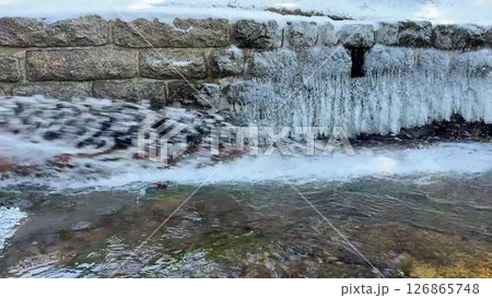 A Frozen Waterfall with an Icy River Flowing Gently Through a Beautiful Wilderness 126865748