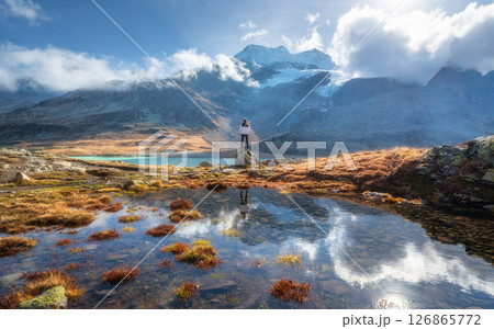 Young woman standing on a rock near lake and snowy mountains Young woman standing on a rock near lake and snowy mountains 126865772