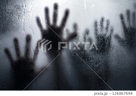 Shadows of desperation against a foggy glass surface in a dimly lit room Shadows of desperation against a foggy glass surface in a dimly lit room 126867694