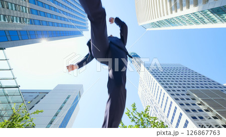 街でジャンプする男性ビジネスパーソンのアオリ構図 街でジャンプする男性ビジネスパーソンのアオリ構図 126867763