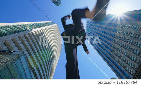 街でジャンプする女性ビジネスパーソンのアオリ構図 126867764