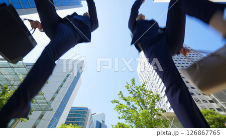 新緑の街でジャンプする男女ビジネスパーソンのアオリ構図 126867765