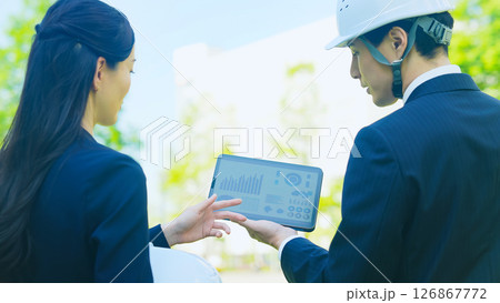 タブレットを見ながら相談する男女作業員 タブレットを見ながら相談する男女作業員 126867772