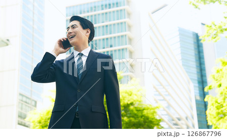 新緑の街でスマホで通話する男性ビジネスパーソン 126867796