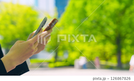 新緑の街でスマホを使う男女ビジネスパーソン 126867826