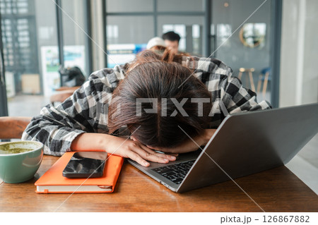 Tired woman with head on laptop in a cafe, showing stress and exhaustion from work. Tired woman with head on laptop in a cafe, showing stress and exhaustion from work. 126867882
