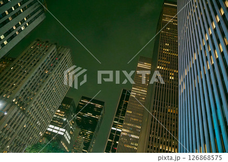 In the heart of Manhattan, towering skyscrapers reach for the night sky, with illuminated windows creating a vibrant urban atmosphere. 126868575
