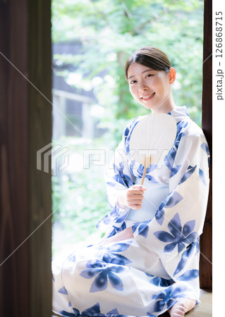 縁側に座る団扇を持った浴衣の女性のカメラ目線 126868715