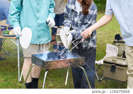 炭火をうちわであおぐ男女の手元 126870868