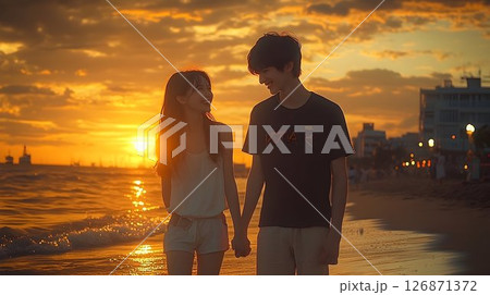 Golden Hour Romance: Young Couple Holding Hands on a Beach at Su 126871372