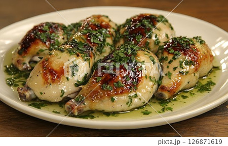 Roasted Chicken Drumsticks with Herb Garnish on a White Plate, C 126871619