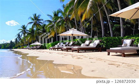 Lounge chairs and umbrellas are perfectly arranged on a pristine sandy beach, inviting guests to unwind and soak up the sun's rays at a luxurious tropical resort 126872030