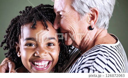 Elderly woman hugging granddaughter, expressing unconditional love and tenderness during heartwarming family moment inside comfortable home environment 126872063