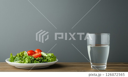 Healthy Lunch Break with Fresh Salad and Glass of Water on Wooden Table Against Gray Background 126872565