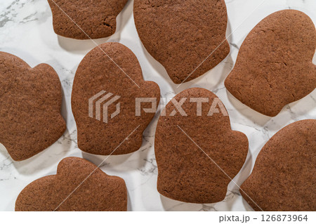 Angled close-up of four Pale Gingerbread Cookies shaped like mittens, highlighting their festive details and rich brown color. 126873964