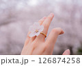 満開の桜を背景に桜の指輪をつける女性の手元 126874258