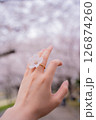 満開の桜を背景に桜の指輪をつける女性の手元 126874260