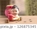 Money bag and thai girl child style of piggy bank with coins on the wooden table. 126875345