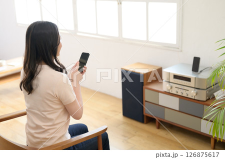スマホを見ながら音楽を聴く女性 スマホを見ながら音楽を聴く女性 126875617