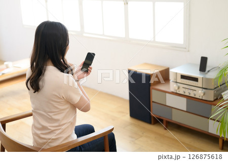 スマホを見ながら音楽を聴く女性 スマホを見ながら音楽を聴く女性 126875618