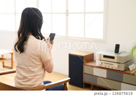 スマホを見ながら音楽を聴く女性 126875619