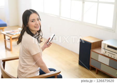 スマホを見ながら音楽を聴く女性 126875620