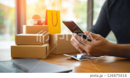 スマートフォンを操作する男性と観葉植物や買い物袋に囲まれたおしゃれなマーケット スマートフォンを操作する男性と観葉植物や買い物袋に囲まれたおしゃれなマーケット 126875818