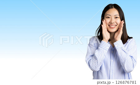 青と白のストライプシャツを着た若い日本人女性が、笑顔で呼びかけている(横長バナー) 126876781